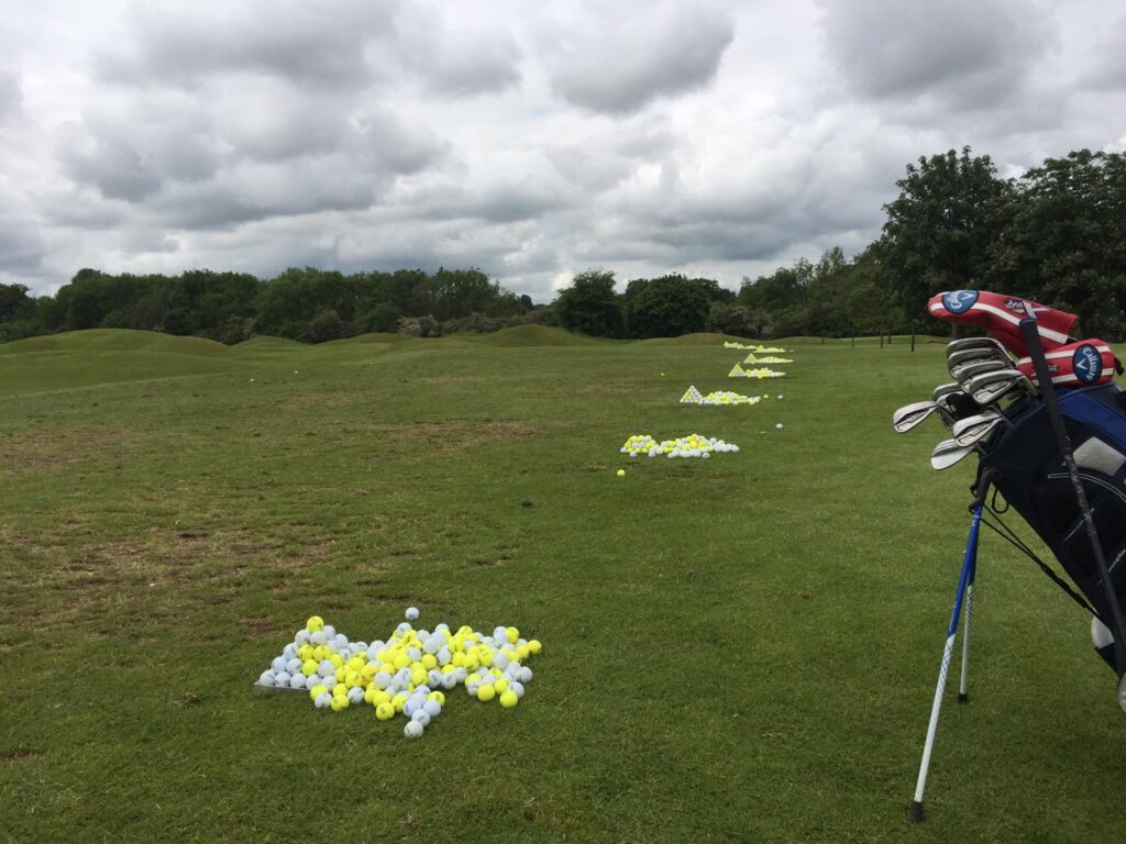 golfer warming up on driving range with golf balls and clubs before a round