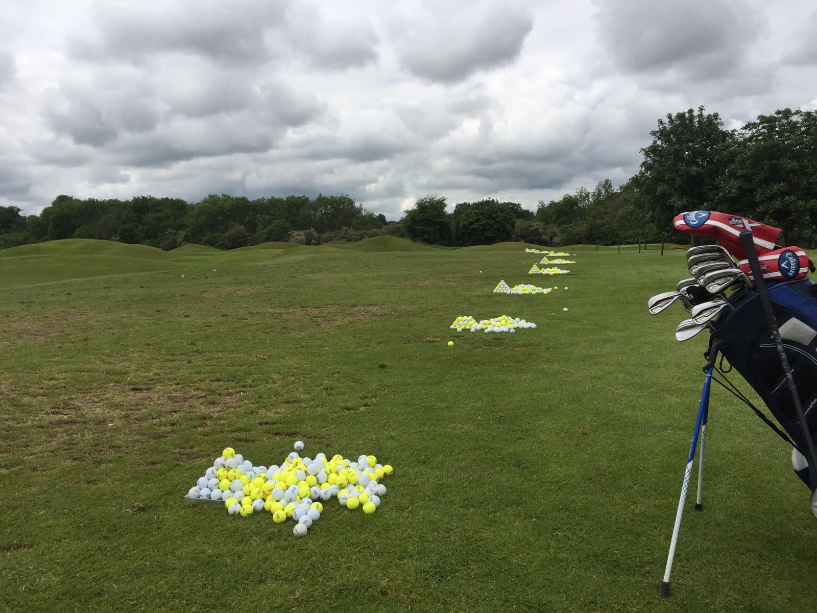 golfer warming up on driving range with golf balls and clubs before a round