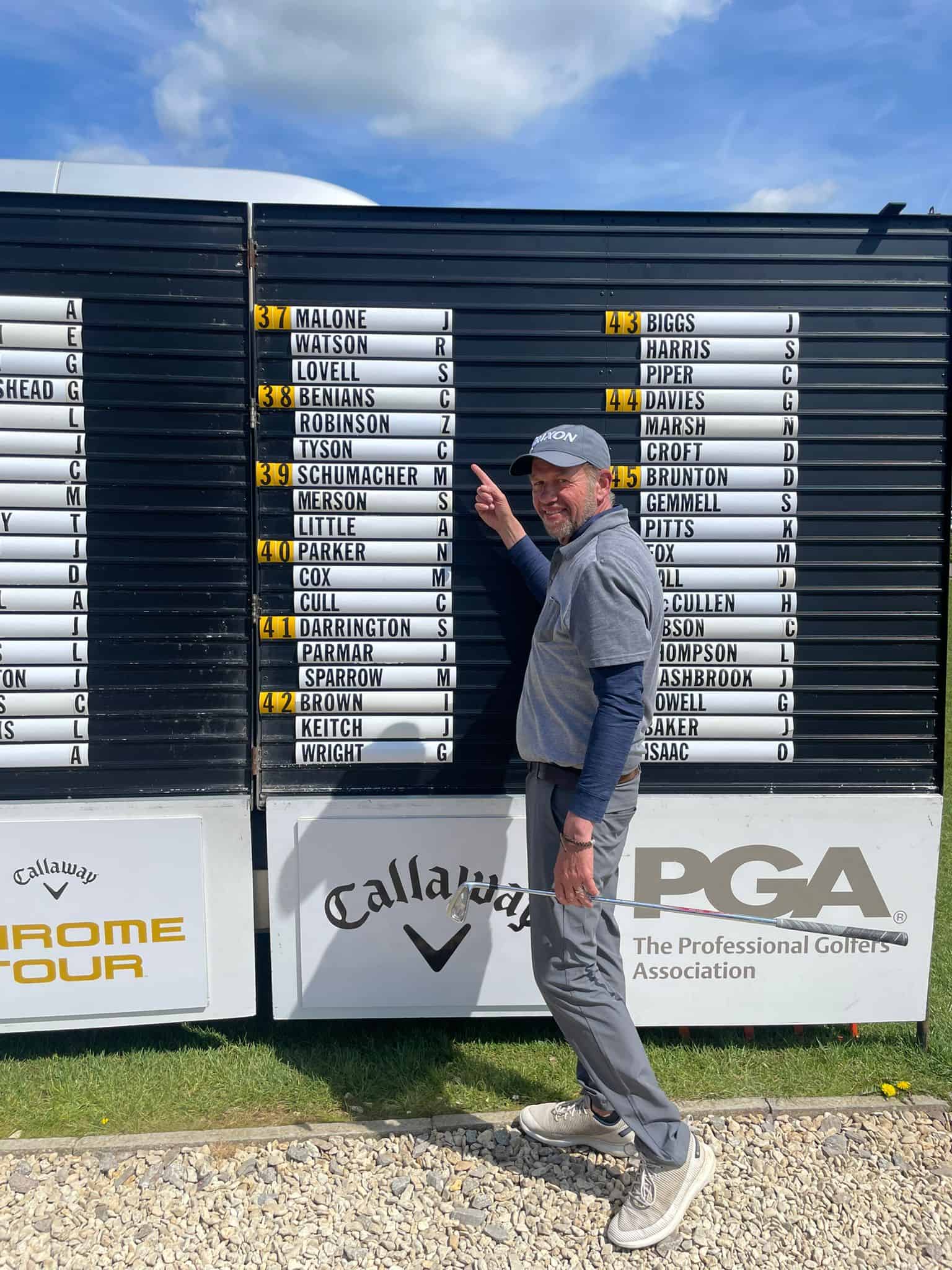PGA Professional Chris “Tyce” Tyson pointing to his name on the tournament draw board at Minchinhampton Golf Club, alongside Chris Benians and Zak Robinson. photo by Steve King