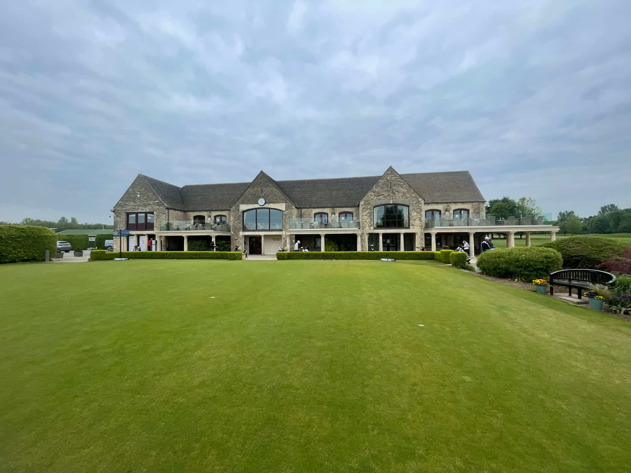 Stone-built clubhouse at Minchinhampton Golf Club overlooking the practice putting green, photographed by Steve King during the 2026 PGA Open Series.